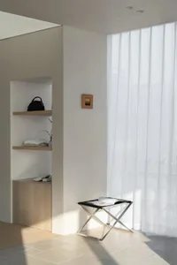 A living room with a white wall, black and white floor plan, a white shelf, a black chair, and a white table, emphasizing organization and functionality