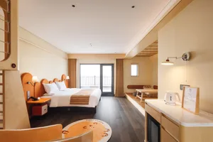 一間現代臥室，配有床鋪、椅子和餐桌，特色是木質地板與窗戶自然光線
