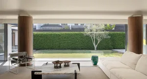 A cozy living room with a white couch, coffee table, and chair, surrounded by natural light from a large window