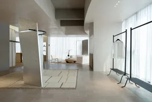 A well-lit modern room with white and gray tones, featuring a couch, chairs, dining table, and a potted plant, creating an inviting and comfortable atmosphere