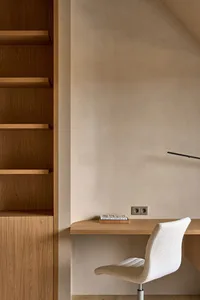 Cozy home office with a desk, chair, bookshelf, and couch in a room with white walls and a warm atmosphere