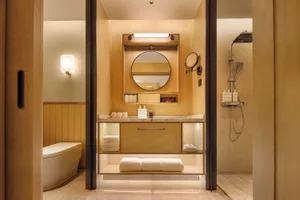 Bathroom with a wooden floor, white toilet, sink, mirror, and shower in a modern space with dim lighting