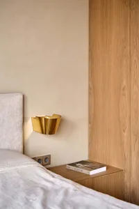 A cozy bedroom with a bed, bookshelf, and wooden wall, creating a warm and inviting atmosphere