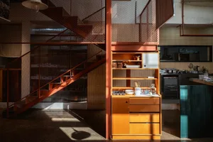 Modern kitchen with wooden cabinets, a metal staircase, and natural light from windows
