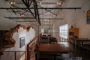 A well-lit restaurant dining area with a wooden floor, wooden table, and chairs, with natural light coming in through the windows