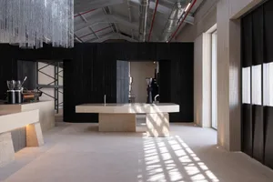A modern kitchen with a marble counter and metal sink, featuring a black and white color scheme and natural light from a window