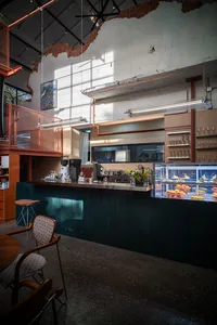 Cozy restaurant with a wooden counter, metal accents, and dim lighting, featuring a mix of decorative items and furniture