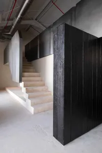 A dimly lit modern staircase with stone steps and a black railing in a hallway