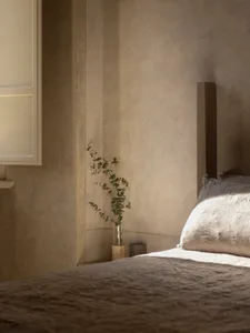 A modern bedroom with a bed, potted plant, and open window, featuring wood and fabric materials in a predominantly neutral color palette