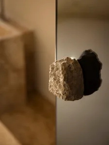A dimly lit bathroom with a large rock in the doorway, creating a mysterious atmosphere