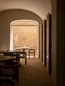 Cozy restaurant with a brick wall, stone floor, wooden tables, and dim lighting