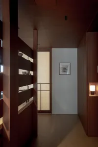 Cozy hallway with a wooden door and bookshelf, dimly lit with warm tones from the wooden elements