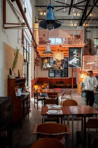 Cozy restaurant with wood and metal elements, dim lighting, and tables and chairs