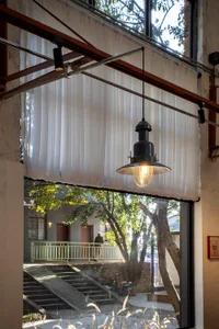 A bright and welcoming living space with a dining table, chairs, couch, and chair, featuring a large window, balcony, and tree outside