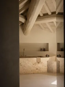 Bathroom with a stone countertop, sink, wall, and ceiling, featuring a modern and minimalist design with natural materials and dim lighting
