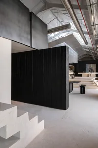 A large, open space with a black wall, a modern staircase made of concrete, and a minimalist design