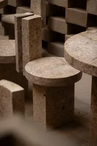 Cozy stone interior with a large stone-like table and concrete benches, dim lighting