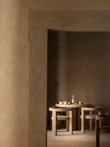 Dining room with a wooden table and chairs, surrounded by multiple bowls and cups, in a warm and inviting atmosphere with natural lighting