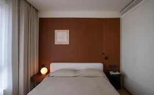 Cozy modern bedroom with a wooden headboard, a bed, and a picture on the wall, dimly lit