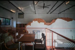Cozy restaurant interior with a brick wall, dining table, chairs, and a bar, lit by dim lighting