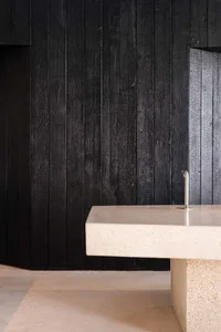Bathroom with a black wall and metal sink, featuring a modern and minimalist design with dim lighting