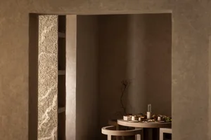 Cozy dining area with a stone table and chairs, surrounded by stone walls, with dim lighting and warm wood accents