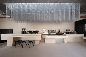 A modern restaurant with a marble counter, kitchen area, and soft lighting, creating a comfortable atmosphere for customers