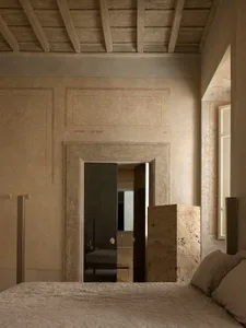 Cozy bedroom with a bed, mirror, and stone wall, dimly lit for a relaxing atmosphere