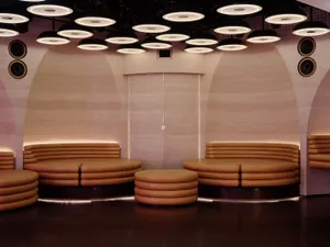A modern living space with a semi-circular seating arrangement, featuring couches and chairs, in a room with a mix of natural and artificial light sources