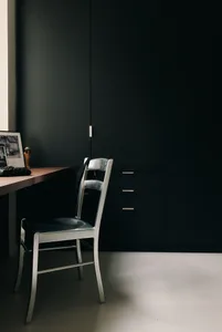 A small, minimalist study area with a chair, desk, and cabinet, featuring a simple and organized layout