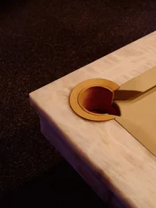A dimly lit room with a wooden table and a brown leather item on it, set against a carpeted floor