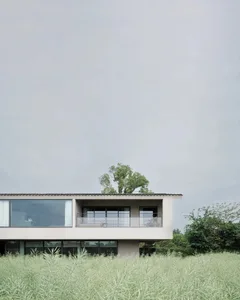 A modern house with a white exterior, large window, and balcony, set in a grassy suburban environment with natural light and warm atmosphere