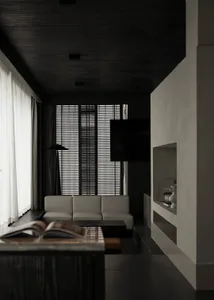 A well-lit living room with a white couch, a black chair, and a television on a stand, set against a black and white color scheme