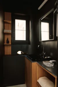 Black and white photograph of a minimalist bathroom with a sink, mirror, and window, featuring a sleek and modern aesthetic