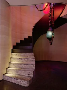 A stone staircase with a metal railing in a well-lit hallway, creating a warm and inviting atmosphere