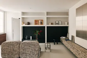 Cozy modern living space with a black and white color scheme, featuring a couch, chair, coffee table, and bookshelf with books, and a vase with flowers adding a pop of color