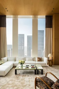 Cozy living space with white furniture, a large window, and natural light, featuring a couch, coffee table, and chair
