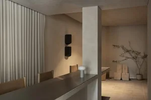 A modern restaurant dining area with a metal counter and a dining table surrounded by chairs, featuring soft and inviting lighting