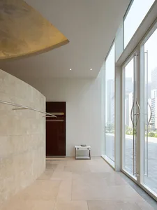 Bathroom with a white tiled floor, brown door, sink, toilet, and natural light from a window
