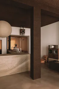 Cozy bar with a wooden chair, concrete counter, and brown and white decor, with a warm and inviting atmosphere