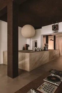 A modern kitchen with a marble counter and stainless steel sink, featuring natural light and a bright atmosphere