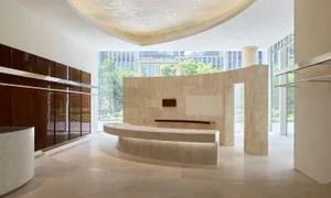 A bright and inviting kitchen with a curved design, featuring a marble counter, surrounded by wood and glass, and filled with natural light