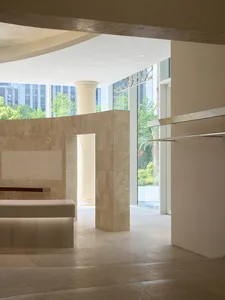 Bathroom with marble walls, a bench, and a shower, featuring a large window and natural light