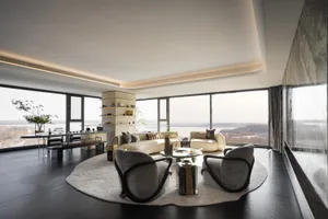 Coastal living room with a couch, chair, and dining table, surrounded by large windows with an ocean view, well-lit and inviting