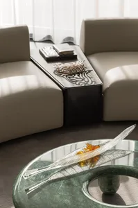 光線充足的現代客廳，配有玻璃茶几、沙發、椅子和一本書，採用玻璃與木質材質