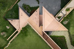 一座獨特三角形住宅建築的照片，具備棕白配色與獨特的建築元素