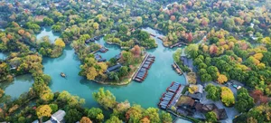 一座現代住宅，周圍環繞樹木與河流，水上有船隻，陽光穿透樹林灑落