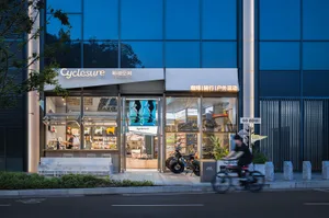 A modern bicycle shop with a glass storefront, a metal bicycle display, and a city street in the background