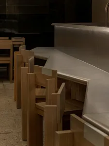 A warm and inviting restaurant dining area with a long wooden table, chairs, and a bench, surrounded by modern decor and comfortable seating