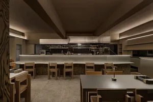 Modern restaurant kitchen with a large island, wood countertops, and dim lighting creating a cozy ambiance